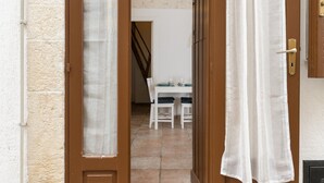 A doorway leading to a dining area with a table and chairs. - Cozy Historic Home by Wonderful Italy (Ostuni)