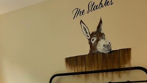 Ein Hotelzimmer mit Bett, Kissen, Decke und einer Wanddekoration – einem Eselskopf.