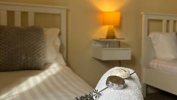 A cozy bedroom with a bed, a bedside table with a lamp, and a wall decoration of sheep.