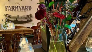 Ein Tisch mit einer Blumenvase, einer Glasgießkanne und einer Kerze.