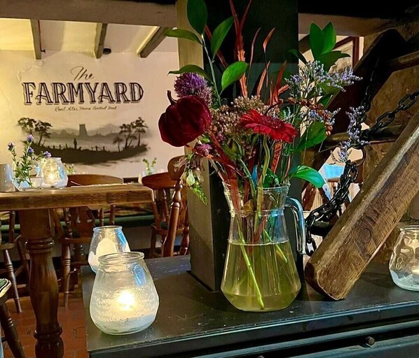A table with a vase of flowers, a glass pitcher, and a candle.