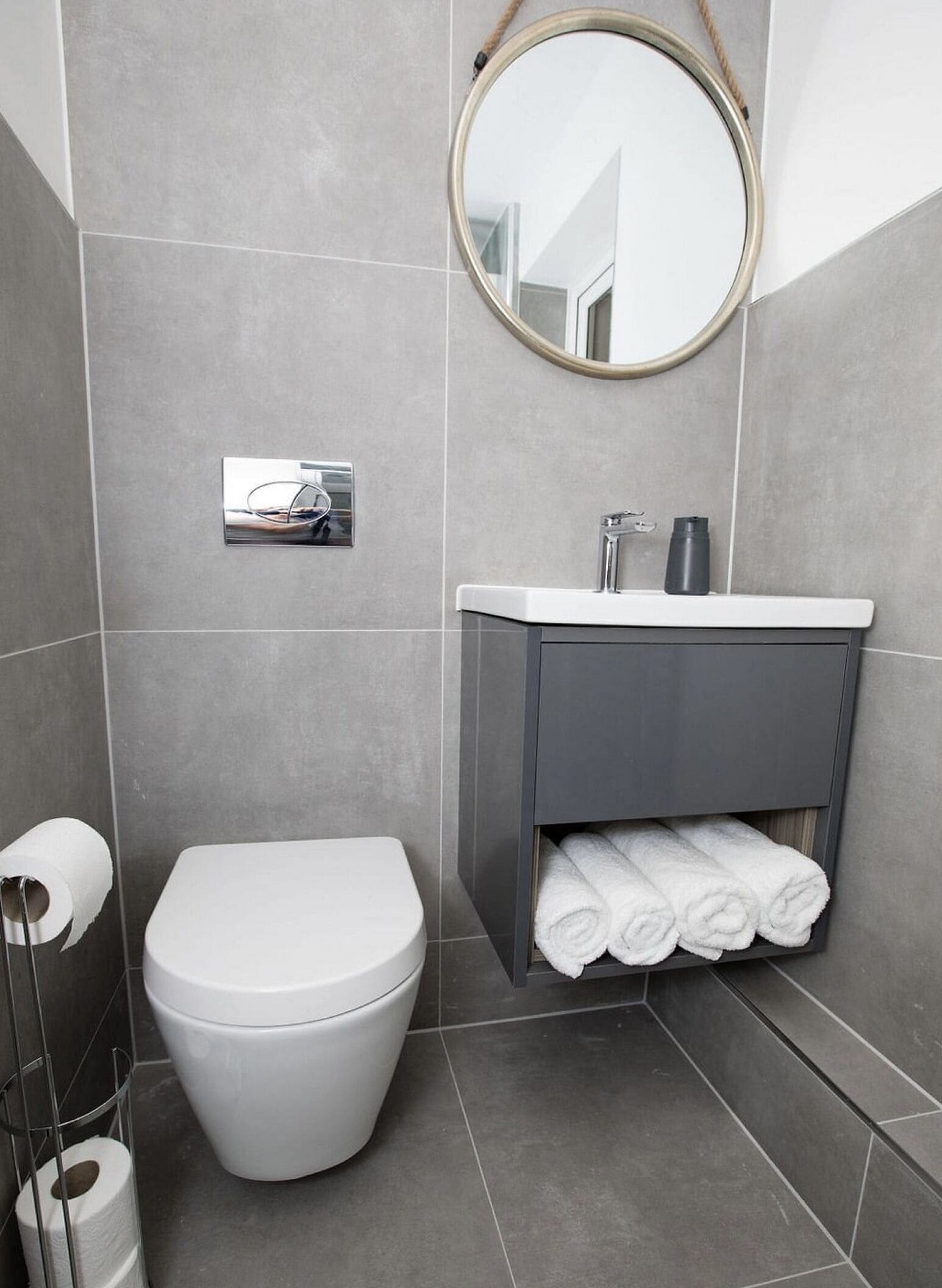 A modern bathroom with a toilet, sink, and towel rack.