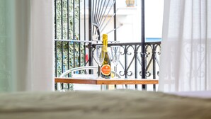 Un balcone con una bottiglia di Prosecco e due bicchieri su un davanzano in legno.