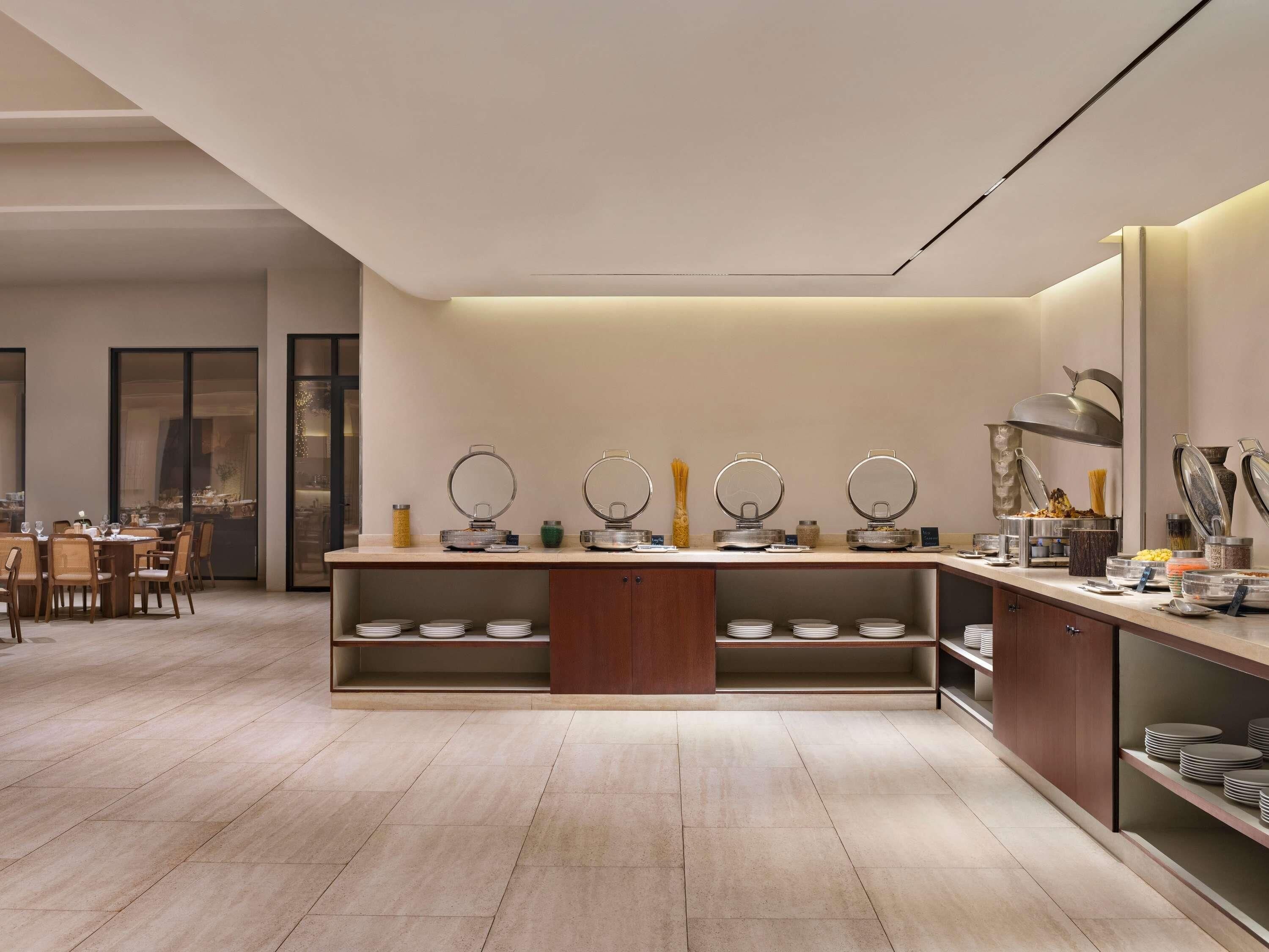 A modern kitchen with a central island, built-in shelves, and a dining area with chairs and a table.