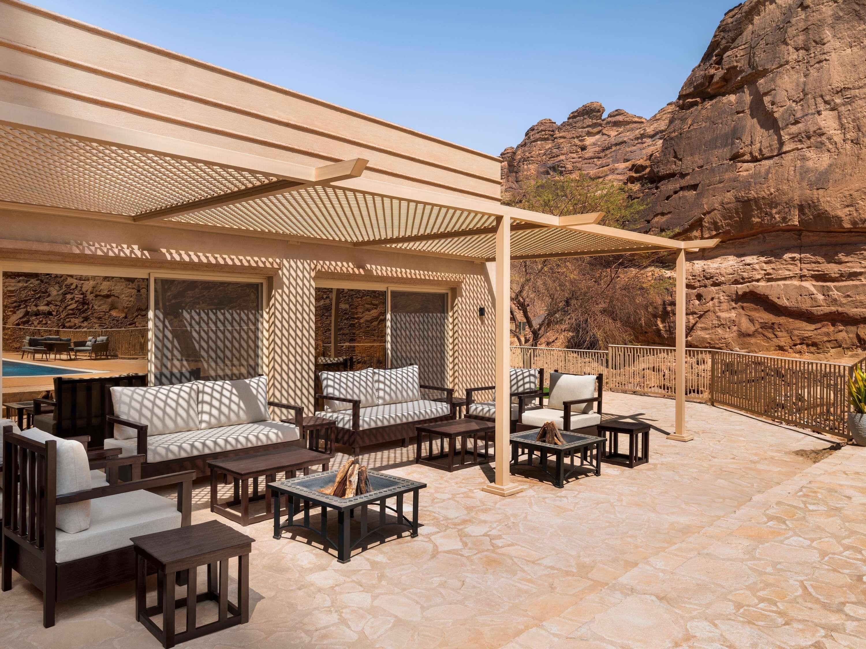Eine Terrasse im Freien mit Sitzgelegenheiten, einer Pergola und Blick auf felsiges Gelände.