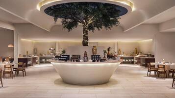 A modern hotel lobby with a central island featuring a tree and a buffet.