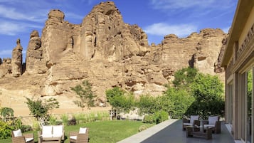 A patio with outdoor furniture, a grassy area, and a view of rock formations.