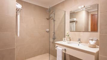 A modern bathroom with a glass shower enclosure, a white sink, and a large mirror.
