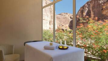 Relax in a serene space with a massage table and a chair, offering a view of the surrounding rocky canyon landscape.