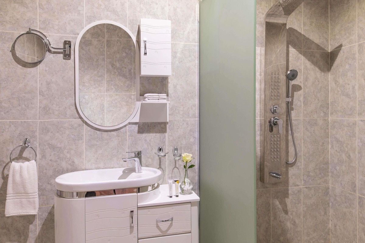 A bathroom with a sink, mirror, towel rack, and shower.