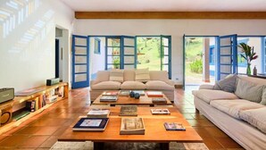 A spacious living room with a sofa, coffee table, and bookshelves. - Fazenda Ressaca: Natural Luxury (Ubatuba)