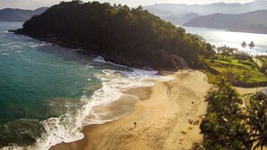A beach with clear turquoise waters, a sandy shore, and a lush green island in the background. - Fazenda Ressaca: Natural Luxury (Ubatuba)