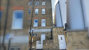 A multi-story building with a brick facade, a visible car club permit sign, and a white door. - Hackney Haven Modern 1 BDR Wifi (London)