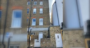A multi-story building with a brick facade, a visible car club permit sign, and a white door. - Hackney Haven Modern 1 BDR Wifi (London)