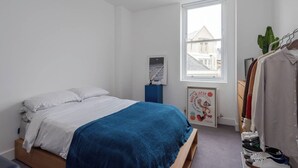A bedroom with a bed, a wardrobe, a window, and a poster on the wall. - Hackney Haven Modern 1 BDR Wifi (London)