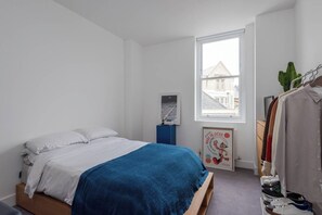 A bedroom with a bed, a wardrobe, a window, and a poster on the wall. - Hackney Haven Modern 1 BDR Wifi (London)