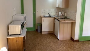 A compact kitchen with a microwave, sink, and cabinets. - 17th century property between the pink granite coast & Lannion, Studio 27m2  (Saint Quay Perros)
