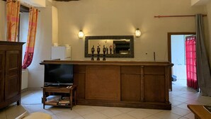 Un salon doté d’un bar en bois, d’une télévision et d’un miroir agrémenté d’objets décoratifs.