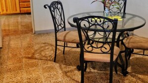A dining area with a round glass table and four chairs with cushioned seats and backs. - Areca Palms (Port Antonio)