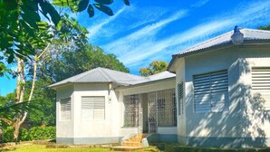 Two white buildings with metal roofs and barred windows, surrounded by greenery. - Areca Palms (Port Antonio)