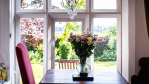 A dining area with a table, chairs, a vase of flowers, and a chandelier. - Lonsdale Villa Retreat (Penrith)