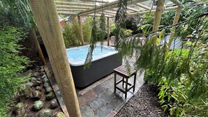 A hot tub under a wooden pergola surrounded by greenery. - Lonsdale Villa Retreat (Penrith)