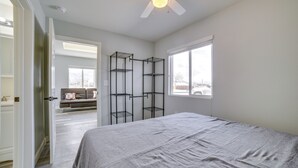 Un dormitorio con una cama, ventilador de techo y ventana.