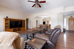 Relax in this spacious living area with a large flat-screen TV, comfortable sofa, and matching armchair.