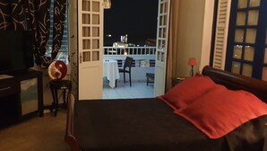 Ein Hotelzimmer mit Bett, Schreibtisch, Fernseher und einem Balkon mit Tisch und Stühlen.