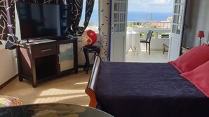 Ein Hotelzimmer mit Bett, Schreibtisch, Fernseher und Meerblick.