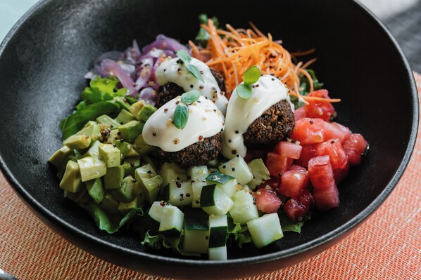 A bowl of food with various vegetables and a sauce.