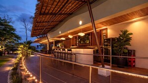 A modern outdoor bar area with a wooden deck, bar stools, and ambient lighting. - Miamar (Quepos)