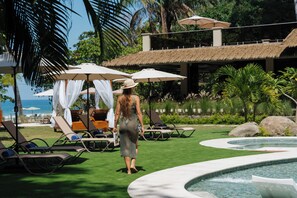 A pool area with lounge chairs, umbrellas, and a clear view of the ocean. - Miamar (Quepos)