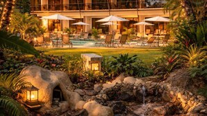 A resort with a pool, lounge chairs, umbrellas, and a stone structure. - Miamar (Quepos)