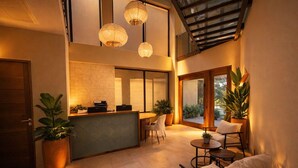 A modern interior with a reception desk, seating area, and potted plants. - Miamar (Quepos)