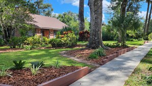 A residential property with a well-maintained lawn, a concrete pathway, and mature trees. - Shady Oaks Estate near Tampa (Brandon)