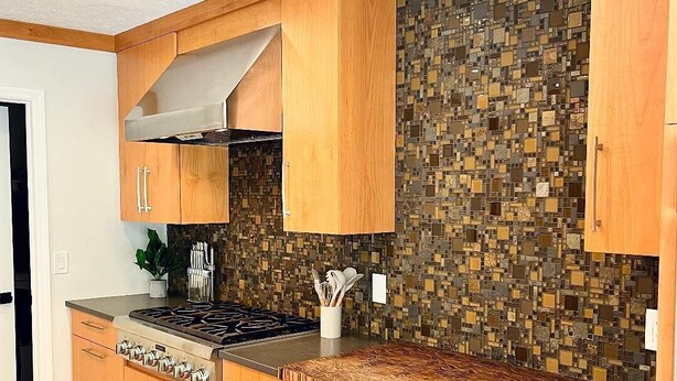 A modern kitchen with wooden cabinets, a tiled backsplash, and stainless steel appliances. - Shady Oaks Estate near Tampa (Brandon)