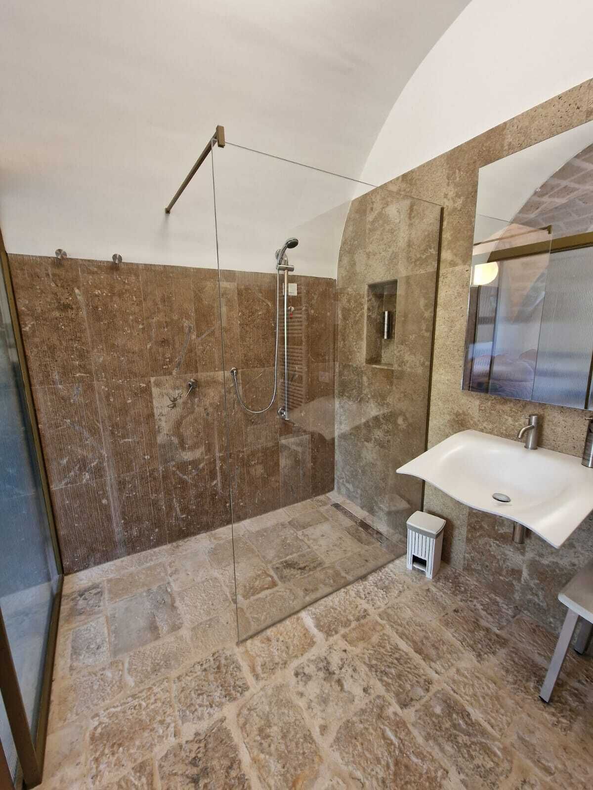 Une salle de bain avec une douche à parois de verre, un lavabo blanc et un grand miroir.