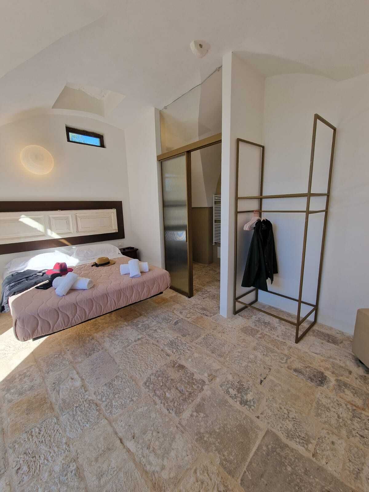 Un dormitorio con cama, armario y baño con ducha.