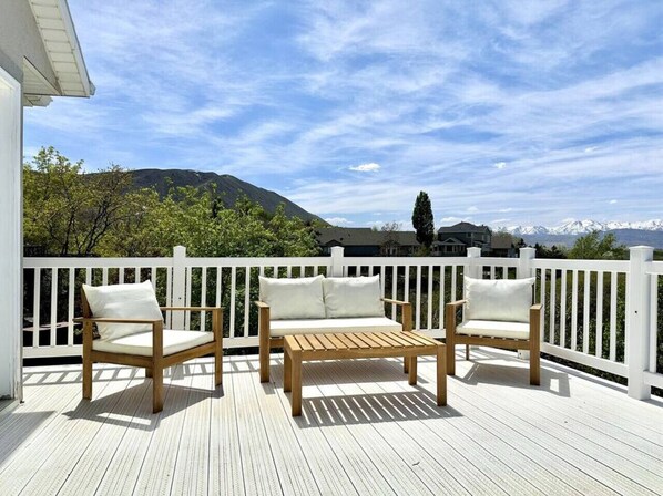 A wooden deck with a white railing, two wooden chairs, and a bench with cushions. - Luxury Retreat with Spectacular Views (Draper)