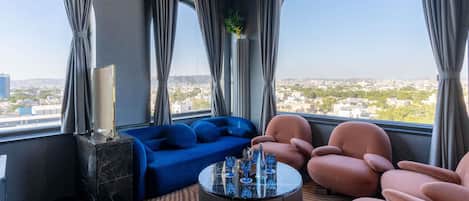 Una sala de estar moderna con un sofá azul, sillones rosados y una mesa de centro de vidrio.