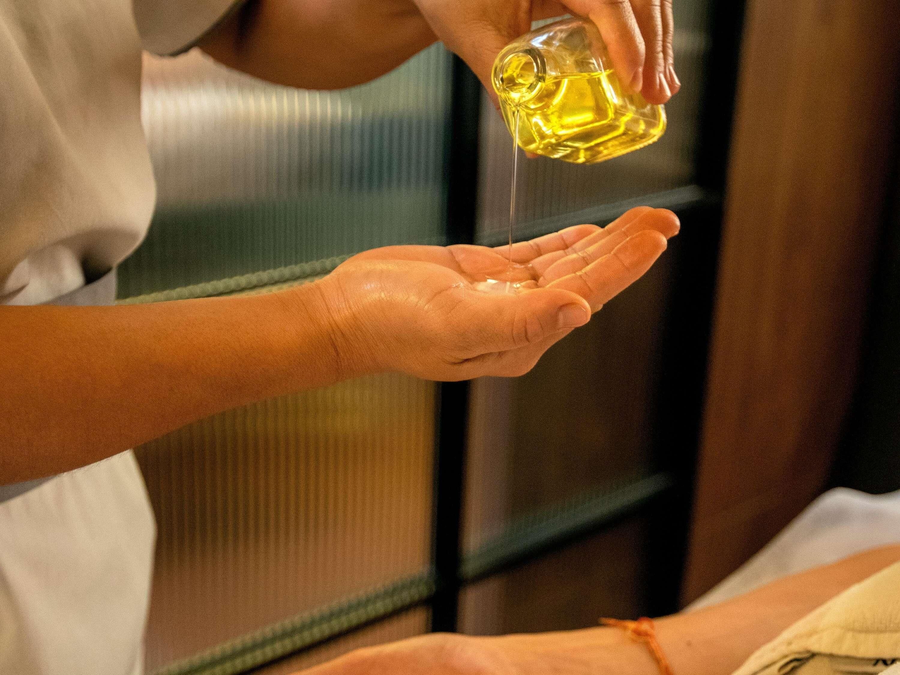 A person pouring oil into another person's hand.