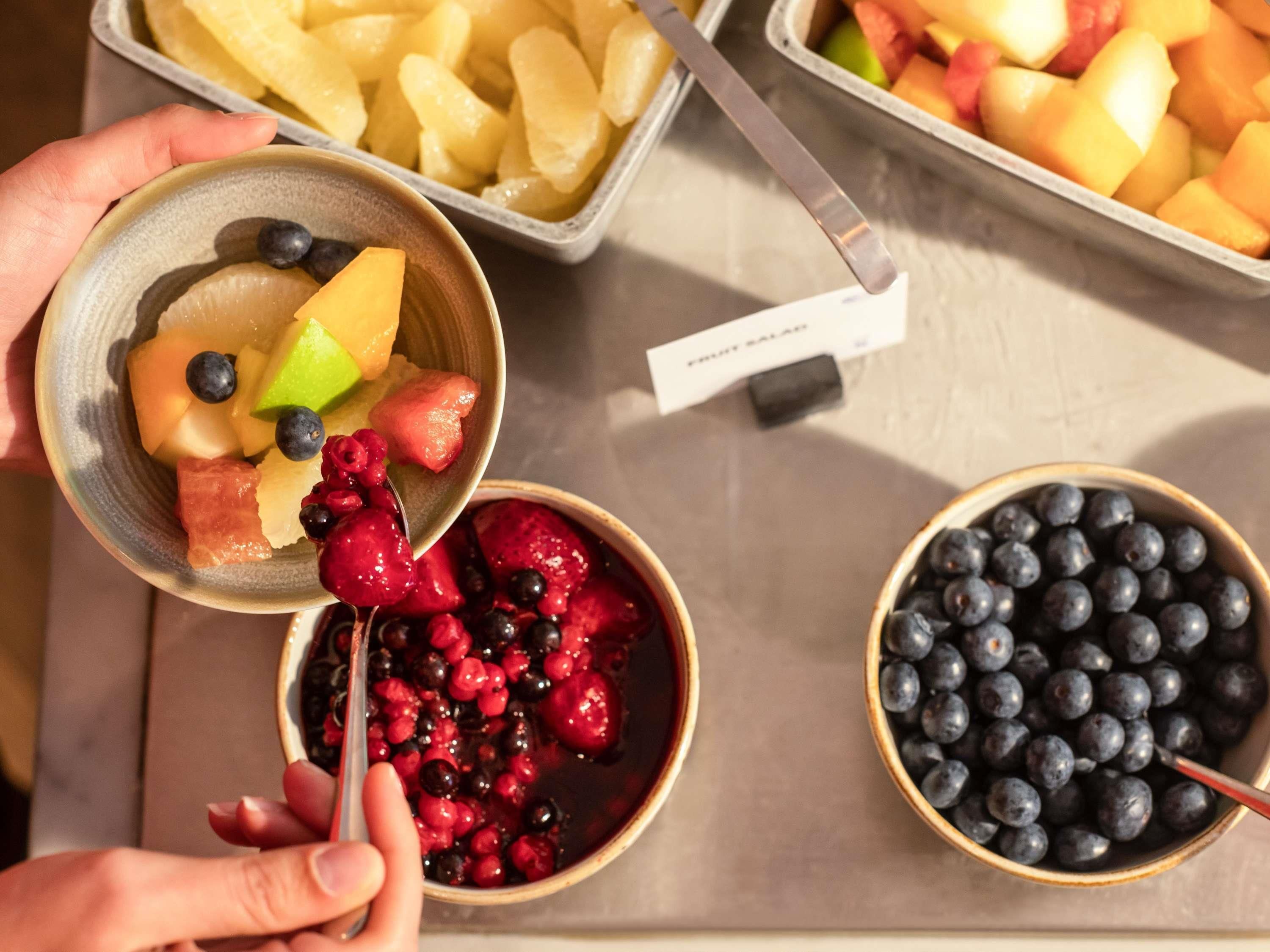 Een fruitsalade met bosbessen, frambozen en stukjes meloen.
