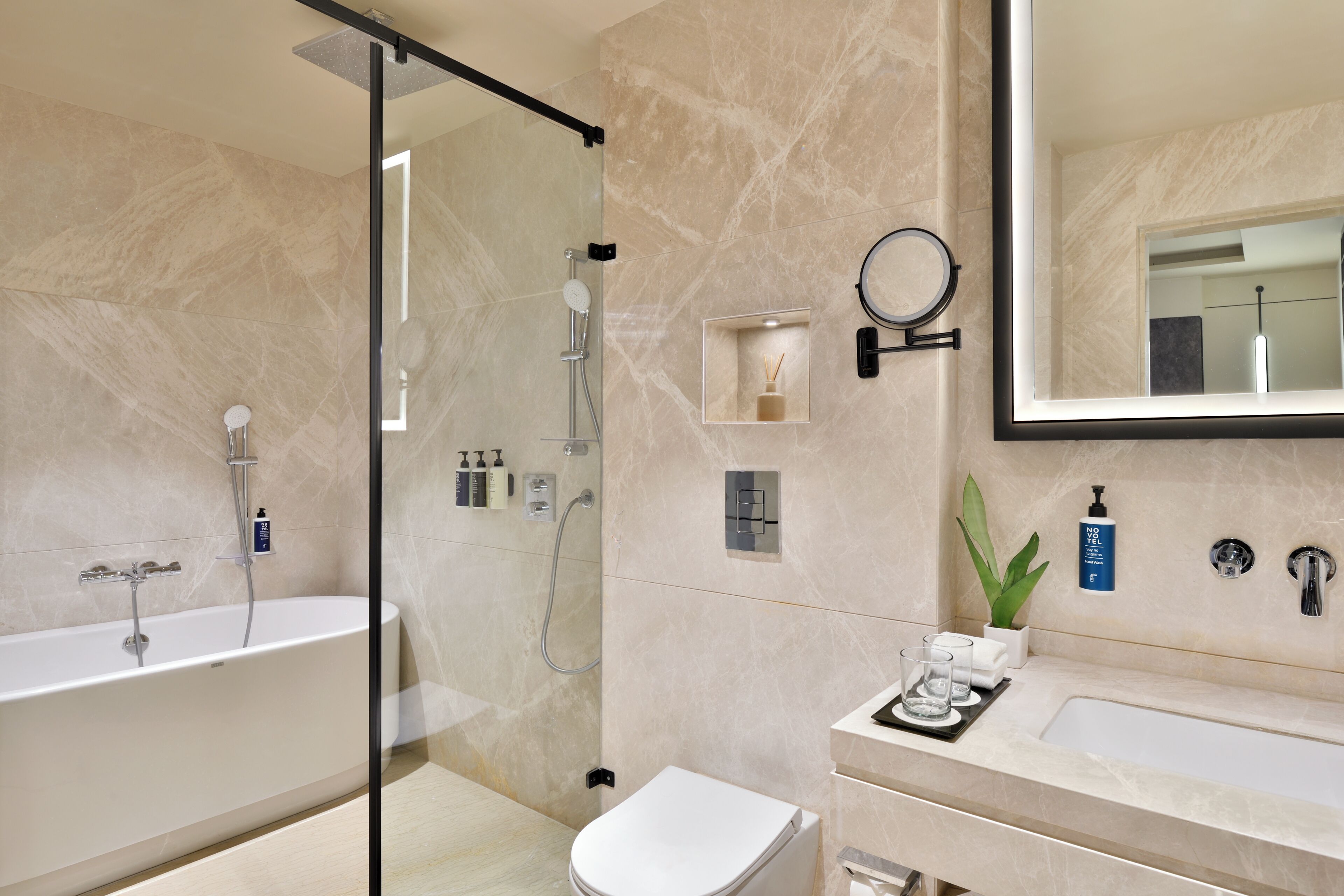 A modern bathroom with a glass-enclosed shower, a freestanding bathtub, and a vanity with a mirror.