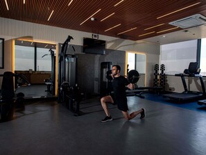 A gym with exercise equipment, a treadmill, and a mirror.