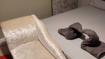 A bed with a grey bedspread, a brown teddy bear, and a red rug.