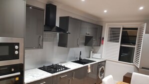 A modern kitchen with stainless steel appliances, a built-in oven, a gas stove, and a washing machine.