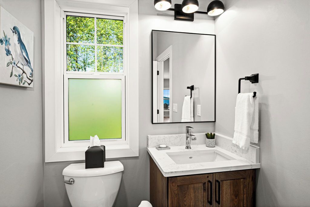A modern bathroom with a toilet, sink, and mirror.