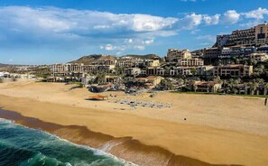 A coastal town with a sandy beach, beachfront villas, and a clear sky. - *Serenity On The Pacific Coast (Resort) (Cabo San Lucas)