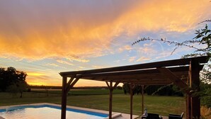 Une terrasse en bois avec une piscine, des chaises longues et une pergola.